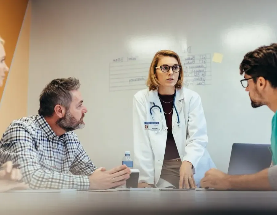 Healthcare leadership team discussing hospital needs with whiteboard in background